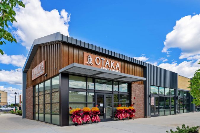 Corner view of Otaka Sushi & Ramen restaurant exterior with large windows and colorful plants by the entrance.