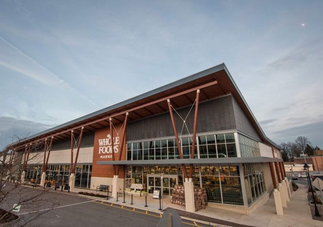 Exterior view of a Whole Foods Market store with large windows and a spacious parking lot.