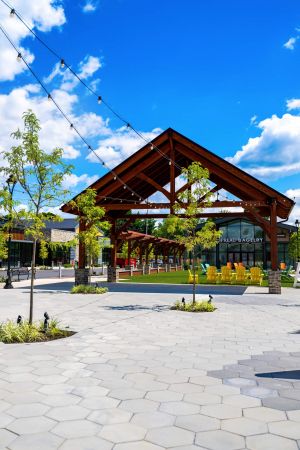 Outdoor pavilion with string lights, yellow chairs, trees, and blue sky with clouds.