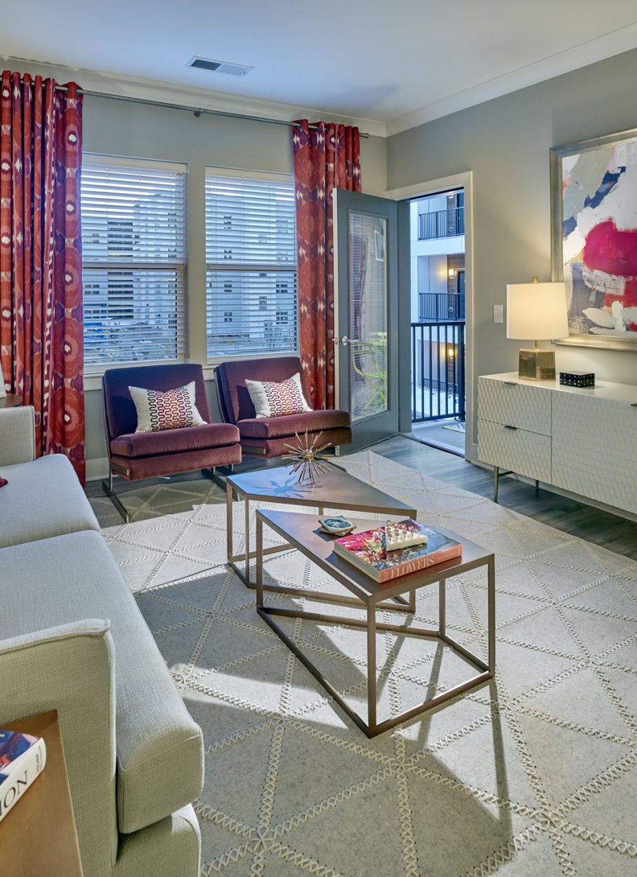 Modern living room with bright red curtains, abstract art, and stylish furniture in soft neutral tones.